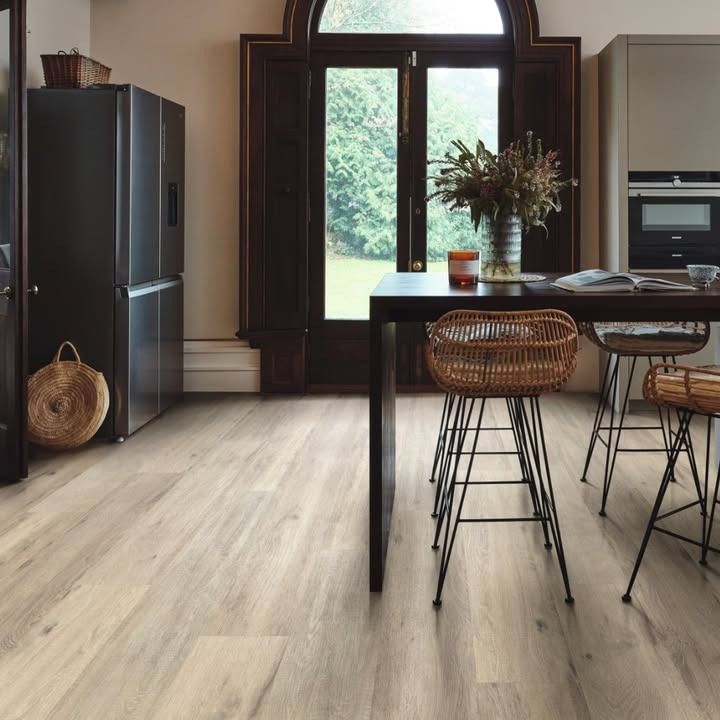 Kitchen with light wood-look flooring, dark cabinetry, and a table with woven stools.