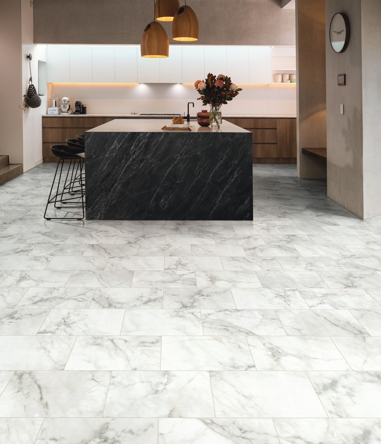 Kitchen with marble-look floor, island with dark countertop, wooden cabinets, and three hanging lights.