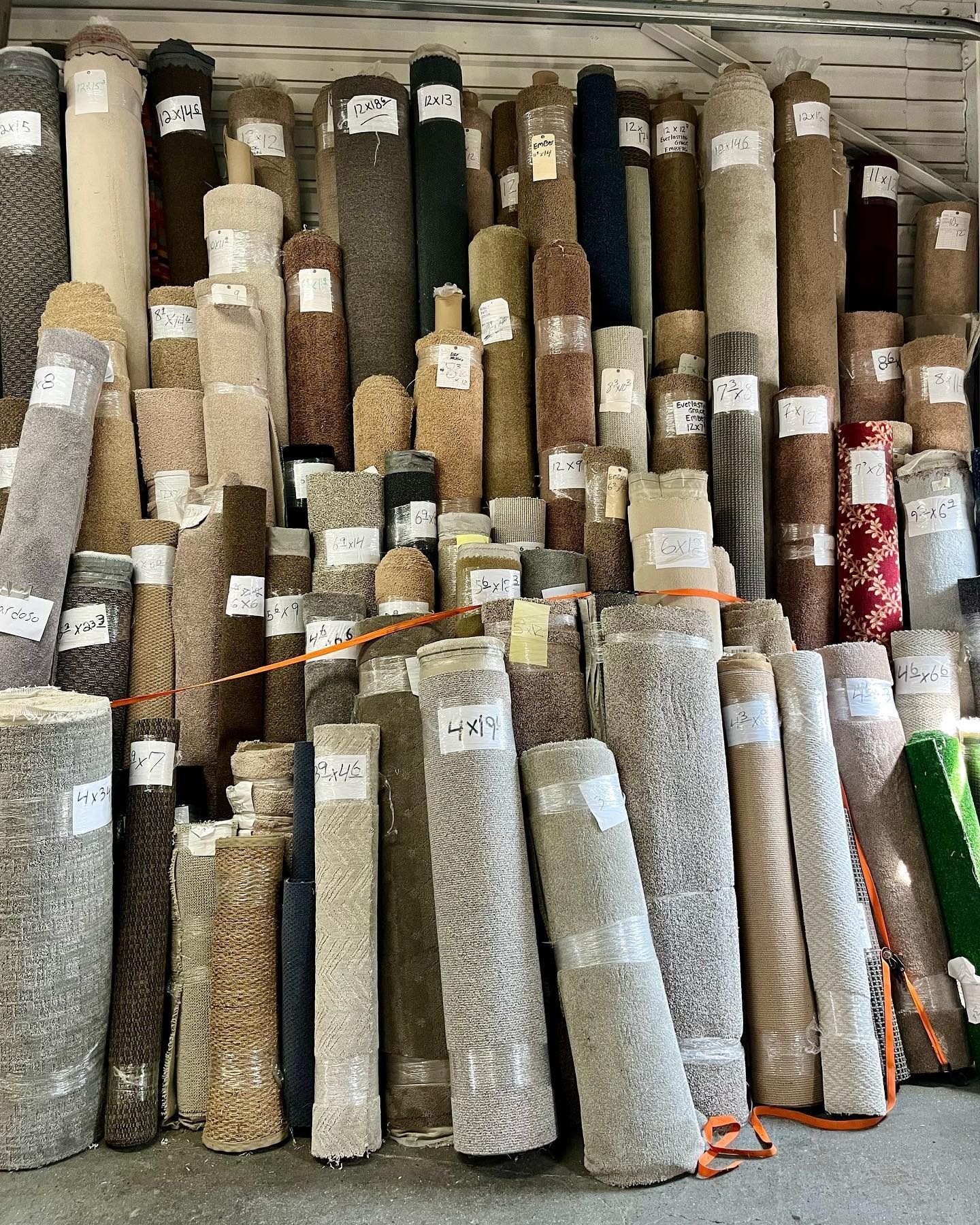 Shelves packed with rolled carpets of various colors and textures, ready for sale.