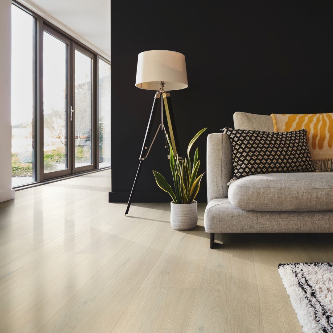 Living room with light wood floor, gray sofa with pillows, black accent wall, and floor lamp.
