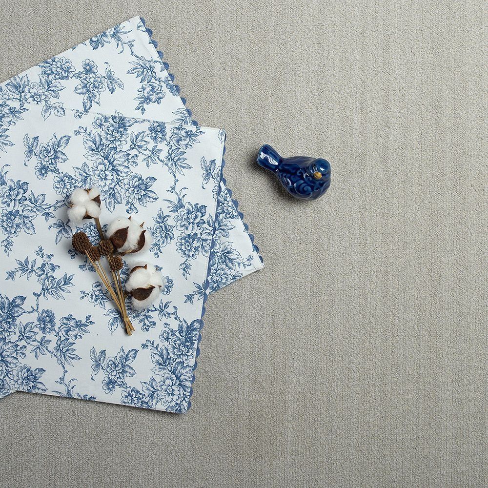 Blue floral napkin with cotton stems and a blue bird figurine on a textured gray surface.