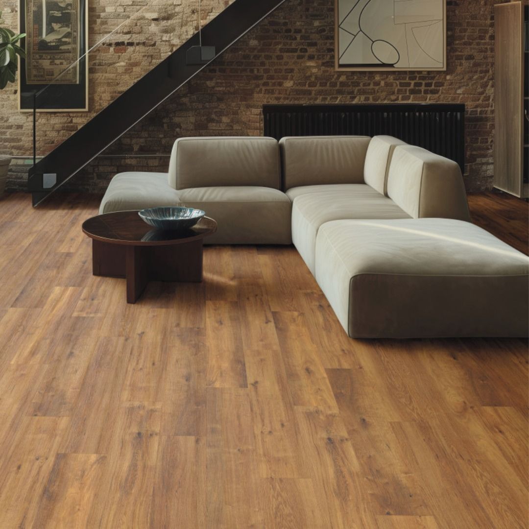 Wooden floor in a room with a sectional sofa, brick wall, and a dark coffee table.