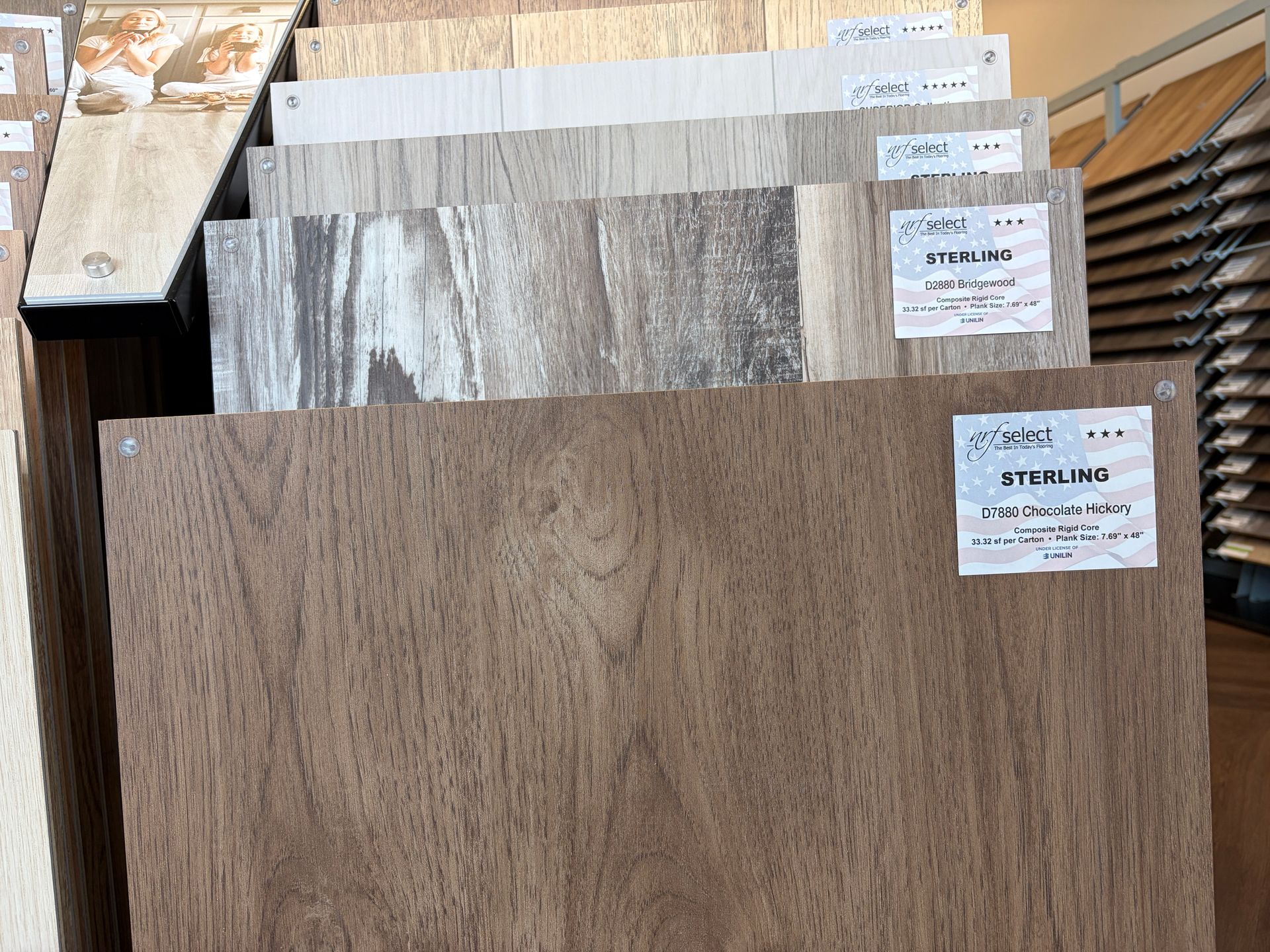 Display of wood-look ceramic tile samples in various shades of brown and gray.