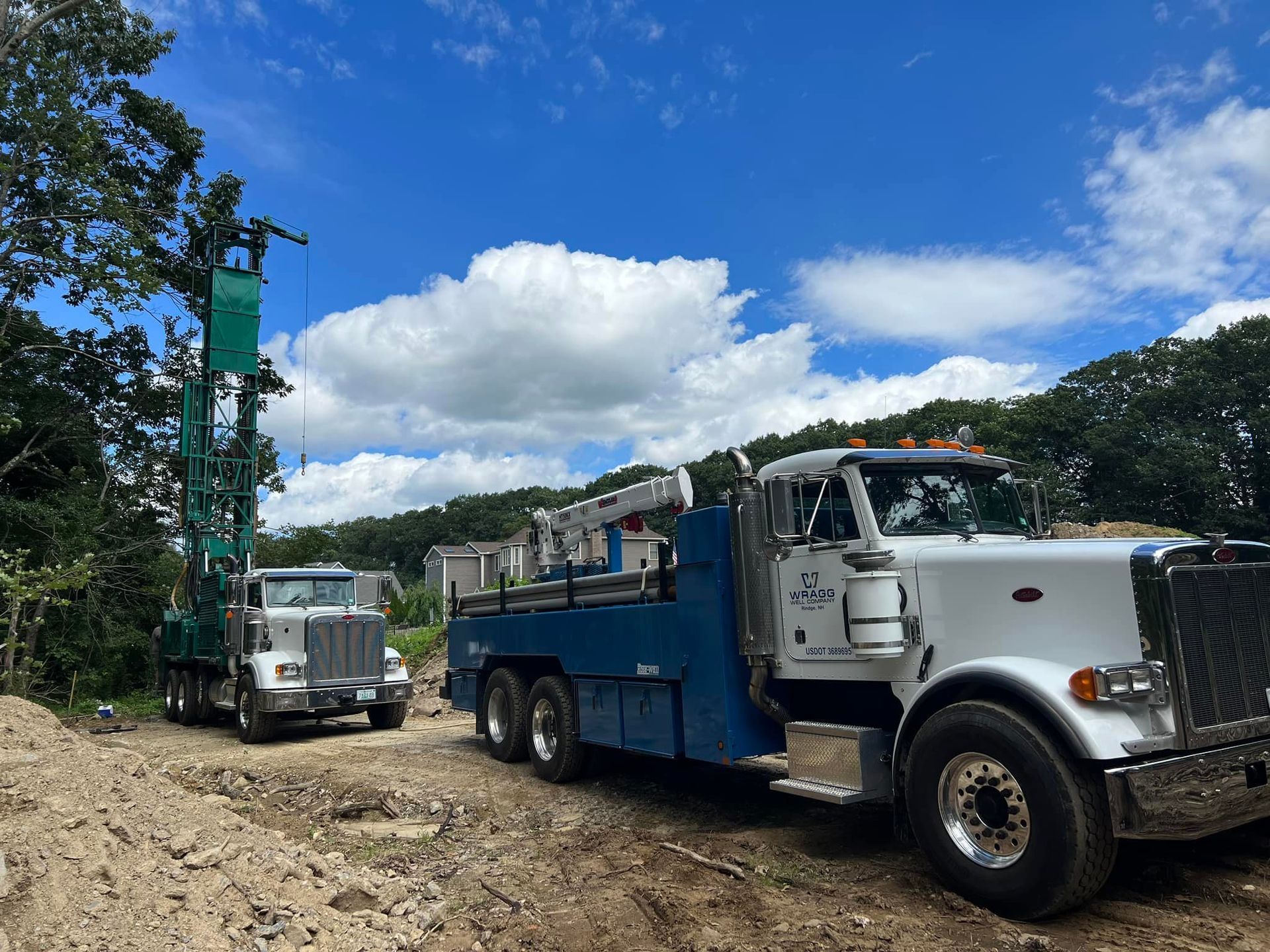 Tow truck on a dirt road hauling a silver vehicle under a blue sky with clouds