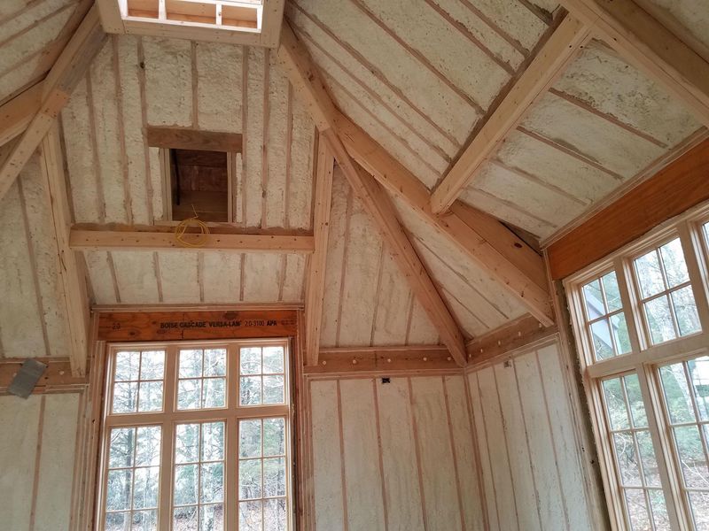 Interior of a wooden-framed room with spray foam insulation visible on walls and ceiling.