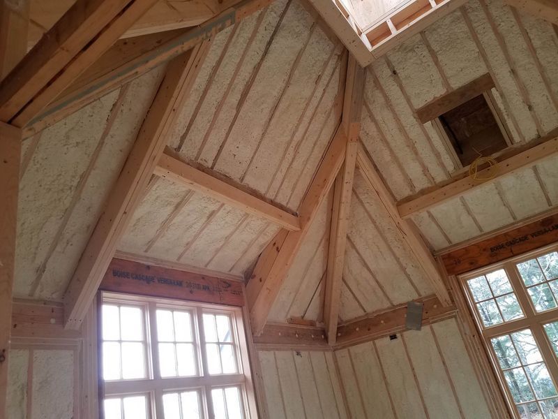 Interior of a wooden structure with spray foam insulation applied to the walls and ceiling.