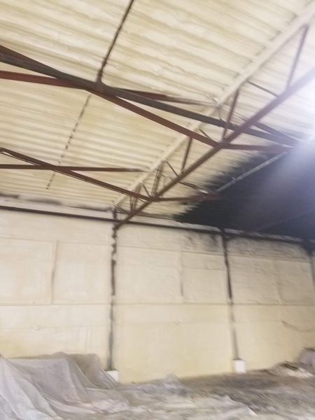 Interior of a warehouse with a white insulated roof and walls, dark support beams.