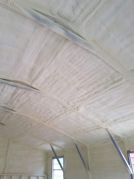 Interior view of a building with spray foam insulation covering the ceiling and walls; light beige color.