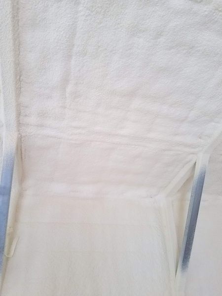 White insulation sprayed on a ceiling, partially covering supports, interior view.