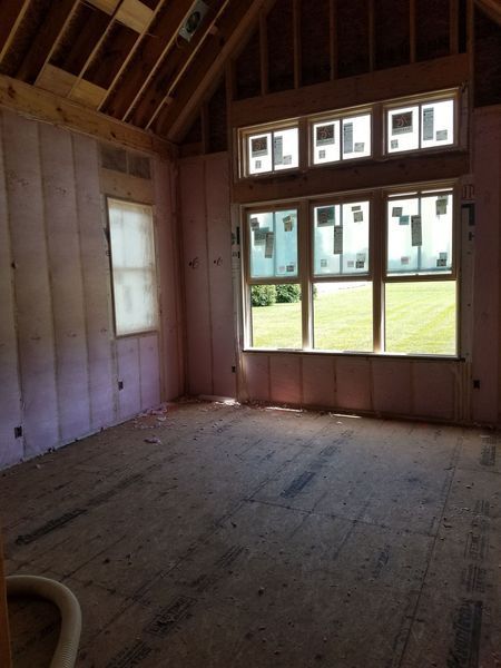 Unfinished room interior with pink insulation, windows, and wood framing.