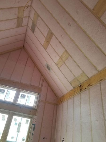 Interior view of a partially constructed room with pink insulation between wooden beams.