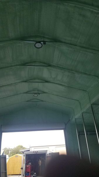 Green interior of a building with arched roof, two lights, and open doorway to outside.