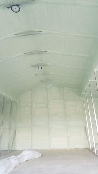 Interior view of a building with spray foam insulation on the walls and ceiling. The space is light green.