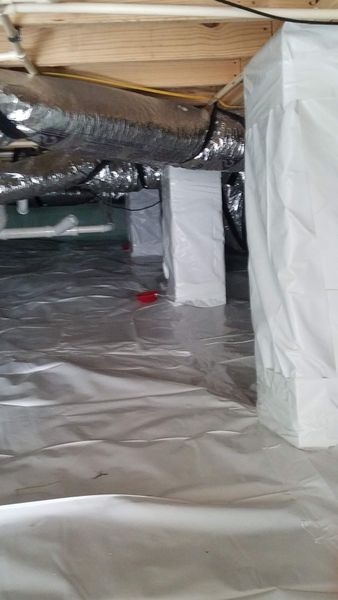 Crawl space with silver vapor barrier on floor, white-wrapped support posts, and ductwork.