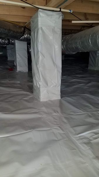 Crawl space with white plastic sheeting and wrapped support columns.
