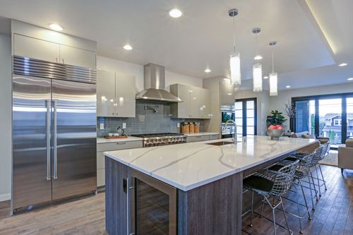 Modern kitchen with stainless steel appliances, large island, pendant lights, and barstools