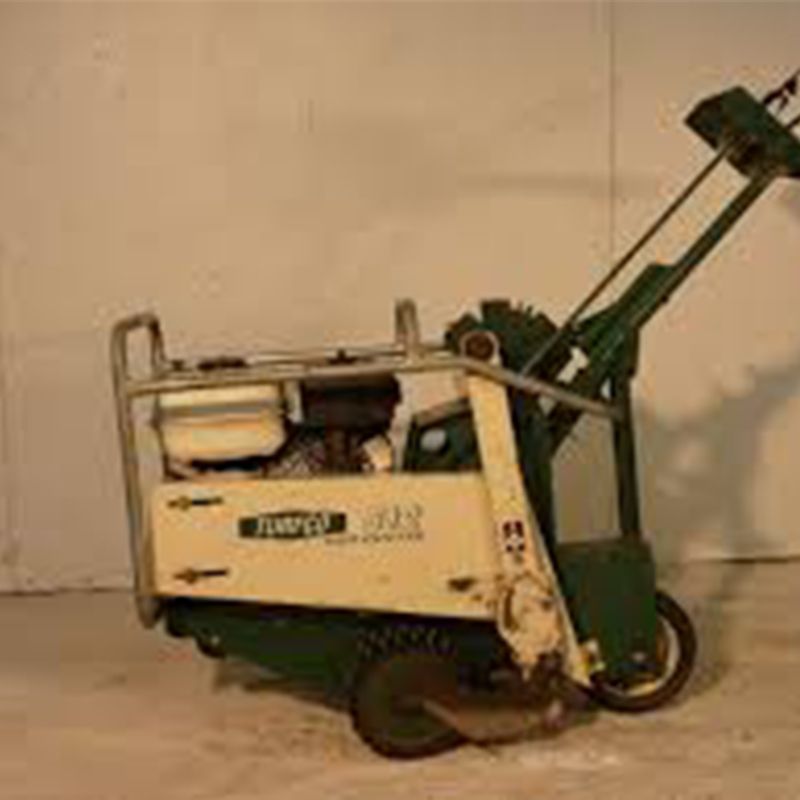 A green and white machine is sitting on a concrete floor.