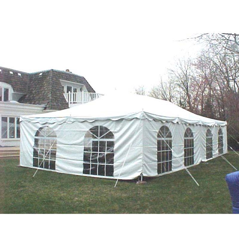 A large white tent is sitting in the grass in front of a house