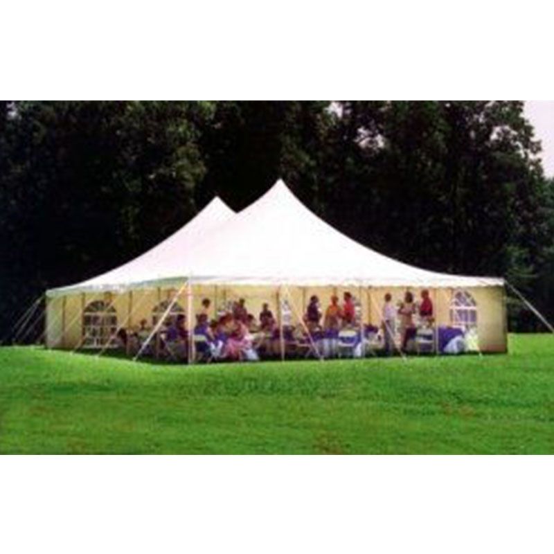 A large white tent is sitting in the middle of a grassy field.