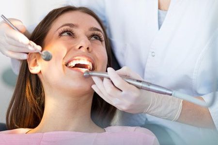 A woman is having her teeth examined by a dentist.