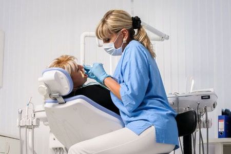 A dentist is examining a patient 's teeth in a dental chair.