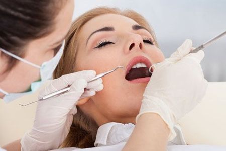 A woman is getting her teeth examined by a dentist.