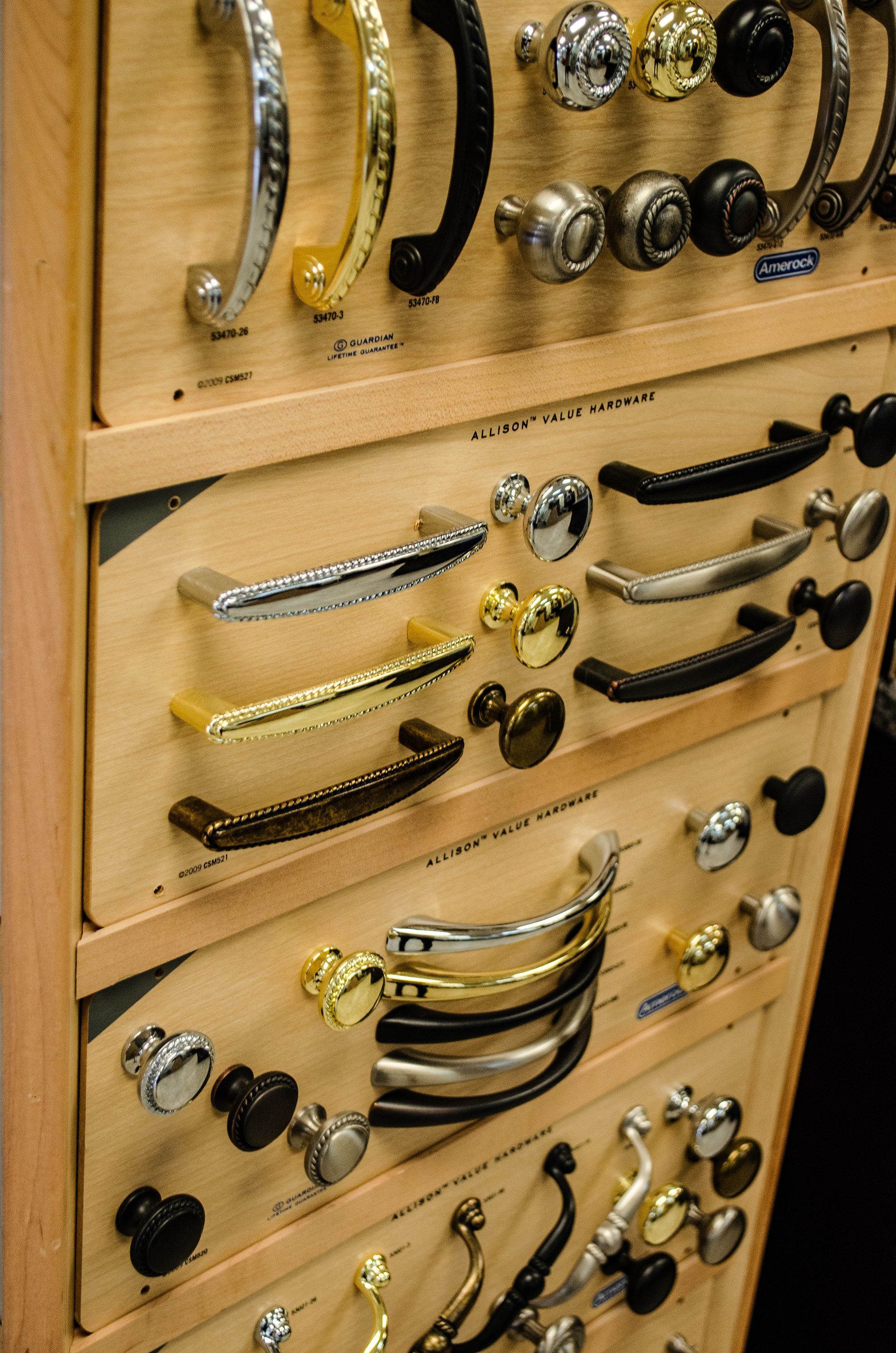 a wooden shelf filled with a variety of drawer handles and knobs