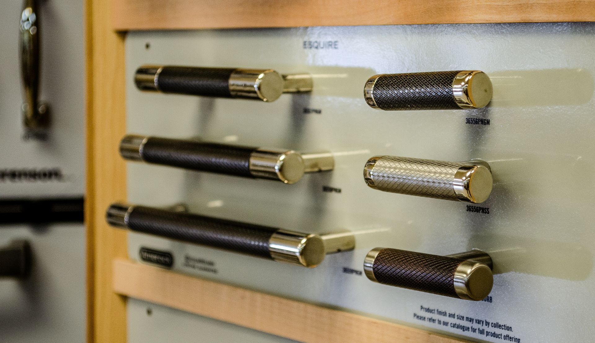 a display of cabinet handles on a wooden shelf