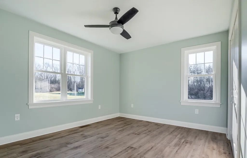 an empty room with a ceiling fan and two windows