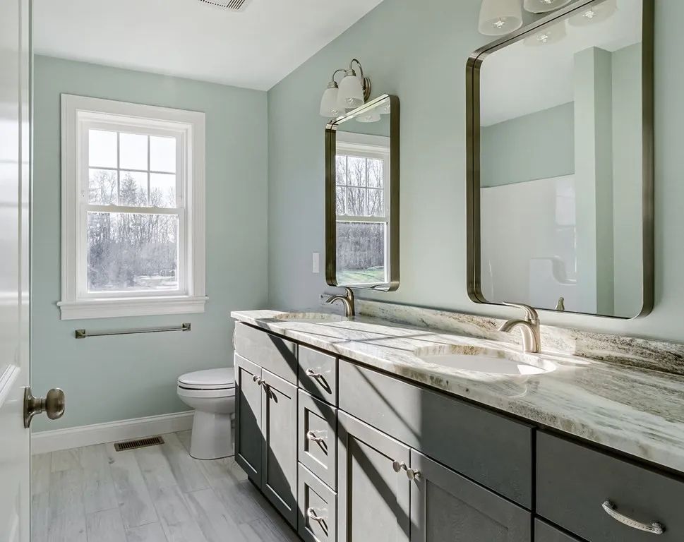 a bathroom with two sinks, a toilet, and two mirrors