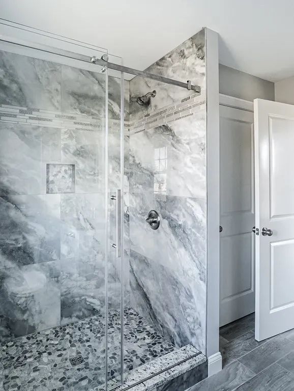 a bathroom with a walk-in shower and a marble wall