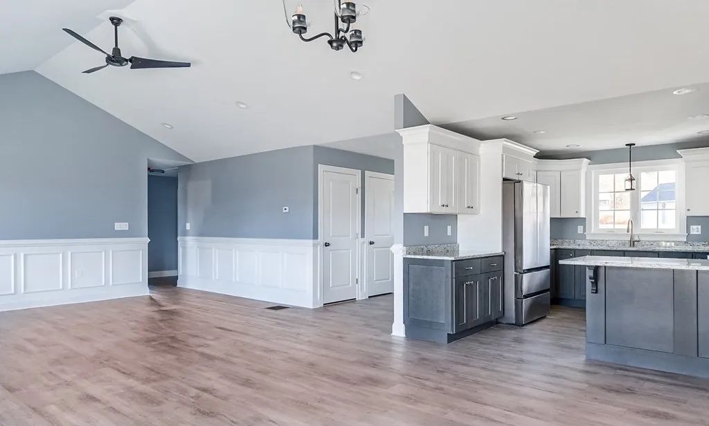 a kitchen and living room in a house with hardwood floors and a ceiling fan
