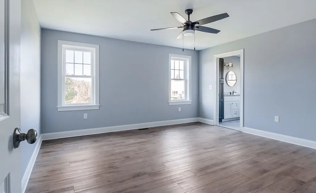 an empty bedroom with hardwood floors and a ceiling fan