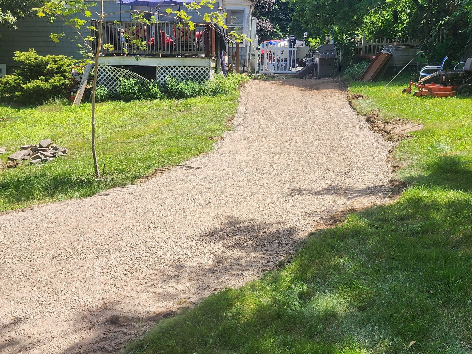 A gravel driveway leading to a house with a deck.
