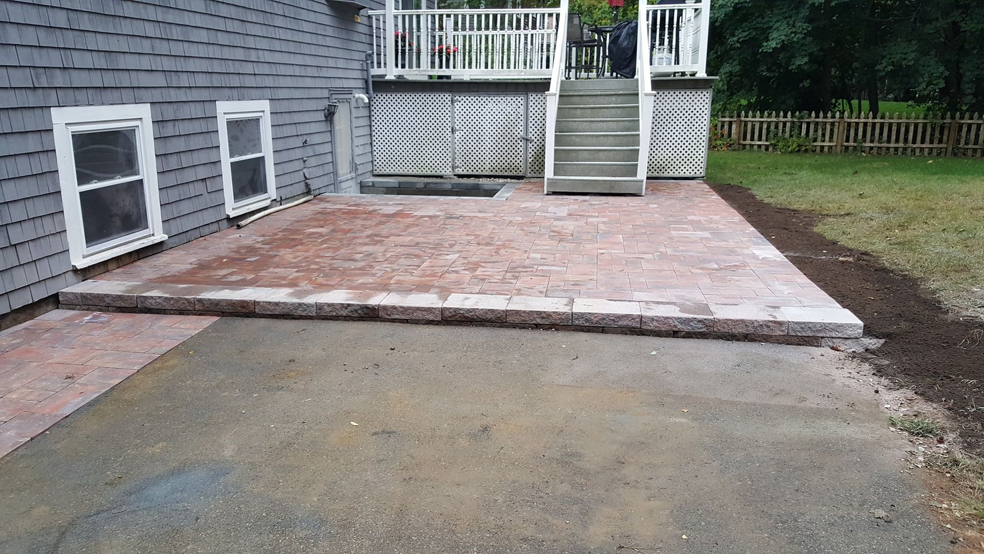 A brick patio is being built in front of a house.