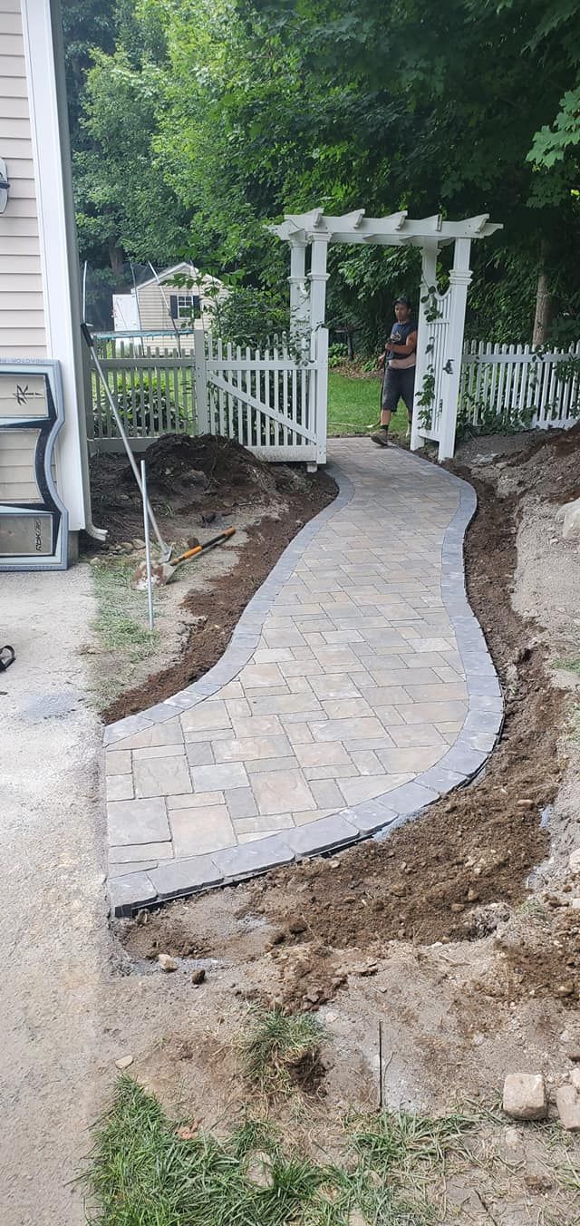 A walkway is being built in the backyard of a house.
