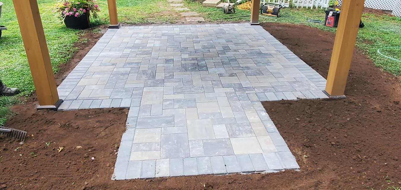 A brick walkway leading to a pergola in a backyard.