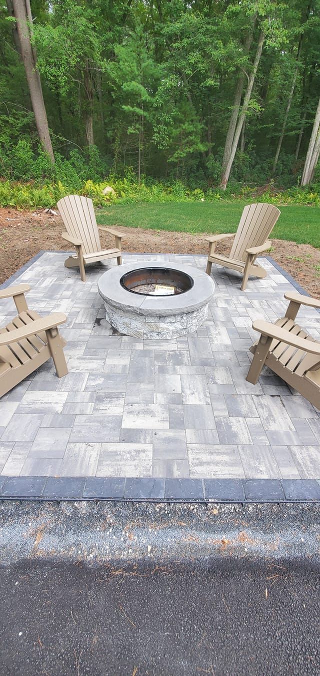 There is a fire pit in the middle of the patio with chairs around it.