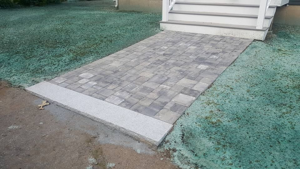 A brick walkway leading to a house with stairs.