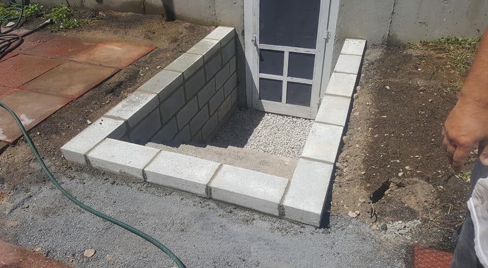 A man is standing next to a brick wall with a hose attached to it.