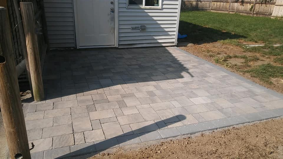 A brick walkway leading to a shed in a backyard.