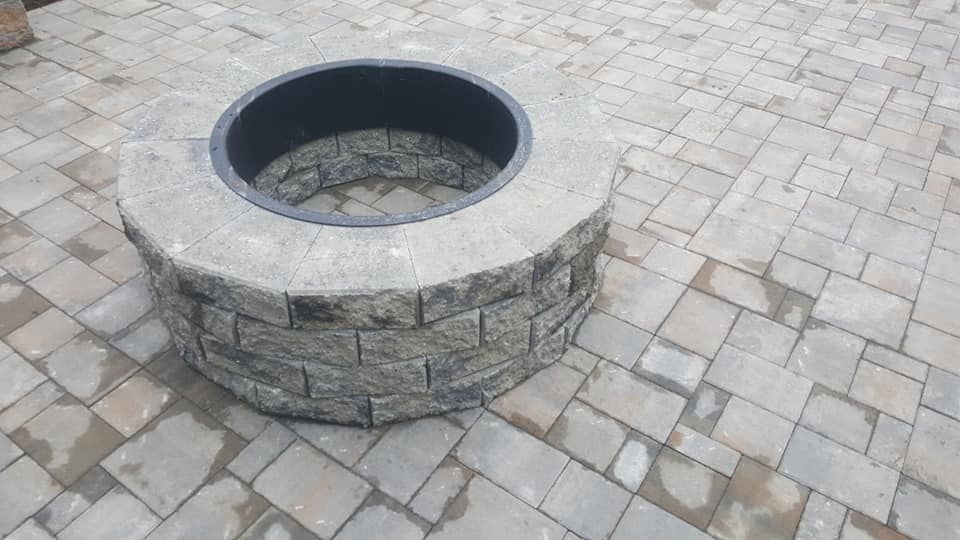 A fire pit is sitting on top of a brick patio.
