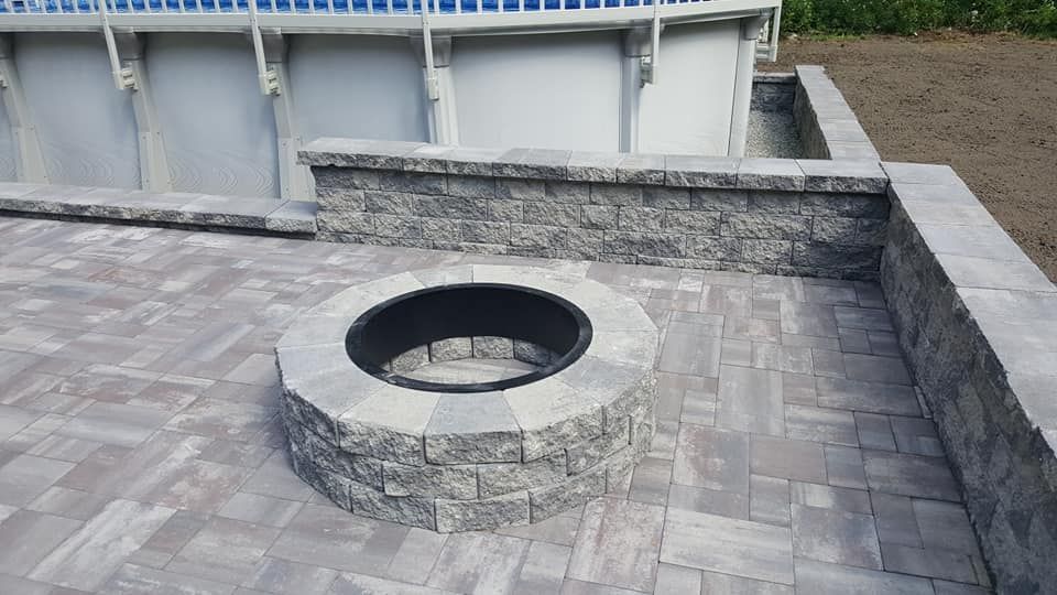 A fire pit is sitting on a patio next to a pool.