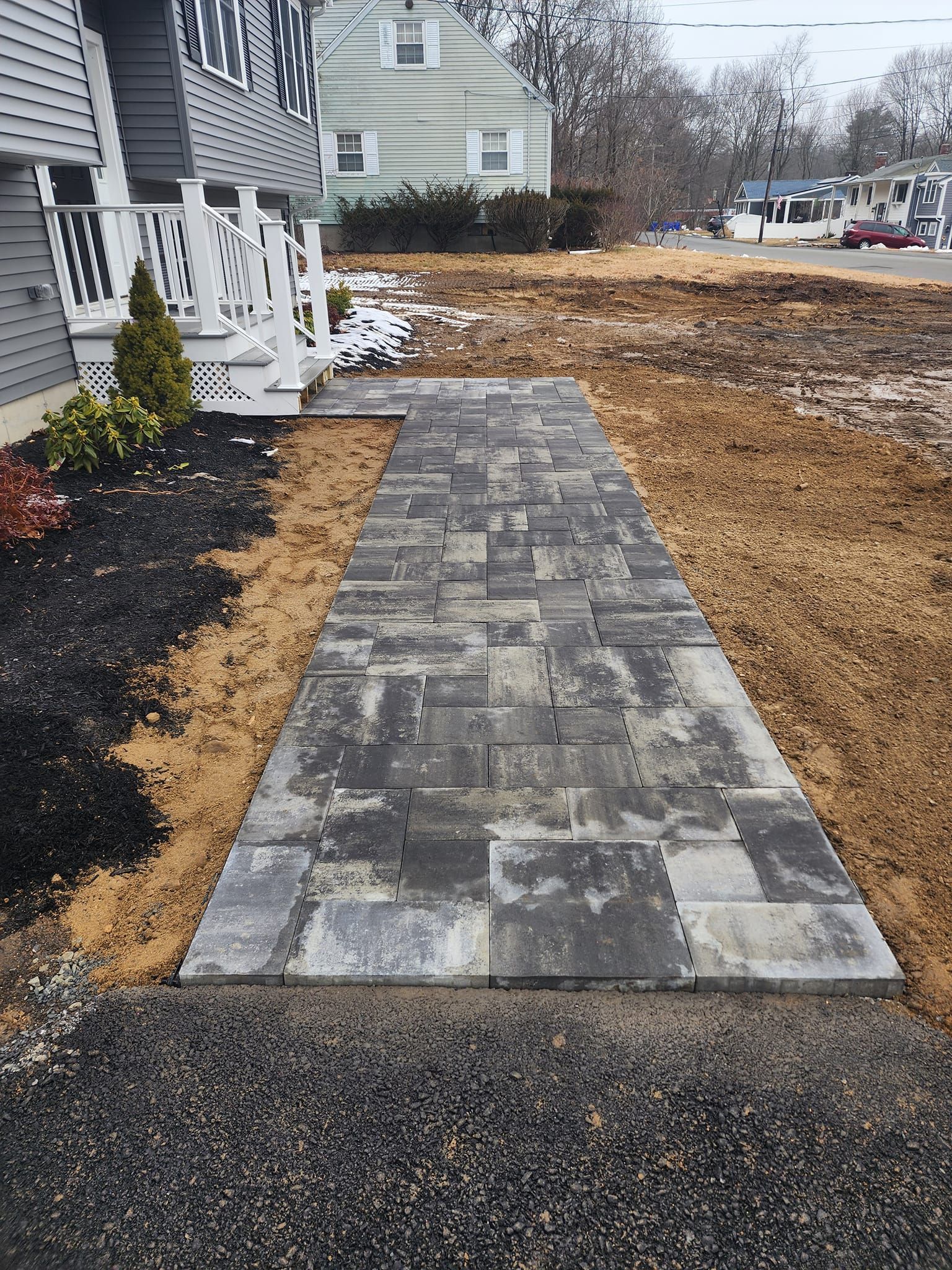 A stone walkway is being built in front of a house.