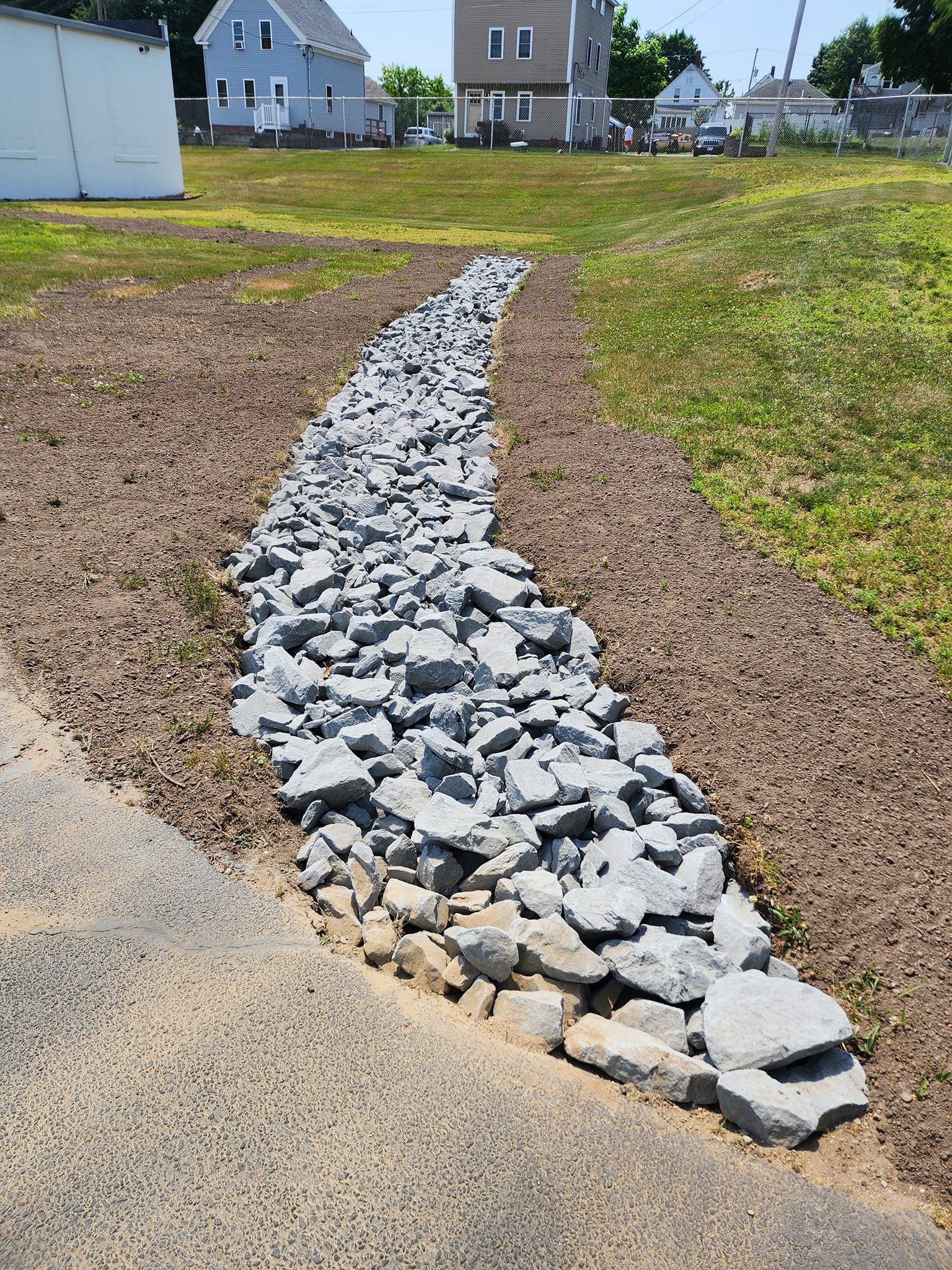 A path made of rocks is going through a grassy field.