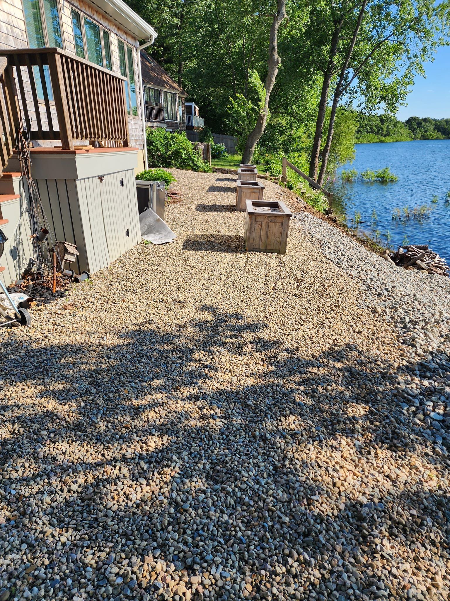A gravel driveway leading to a house next to a lake.