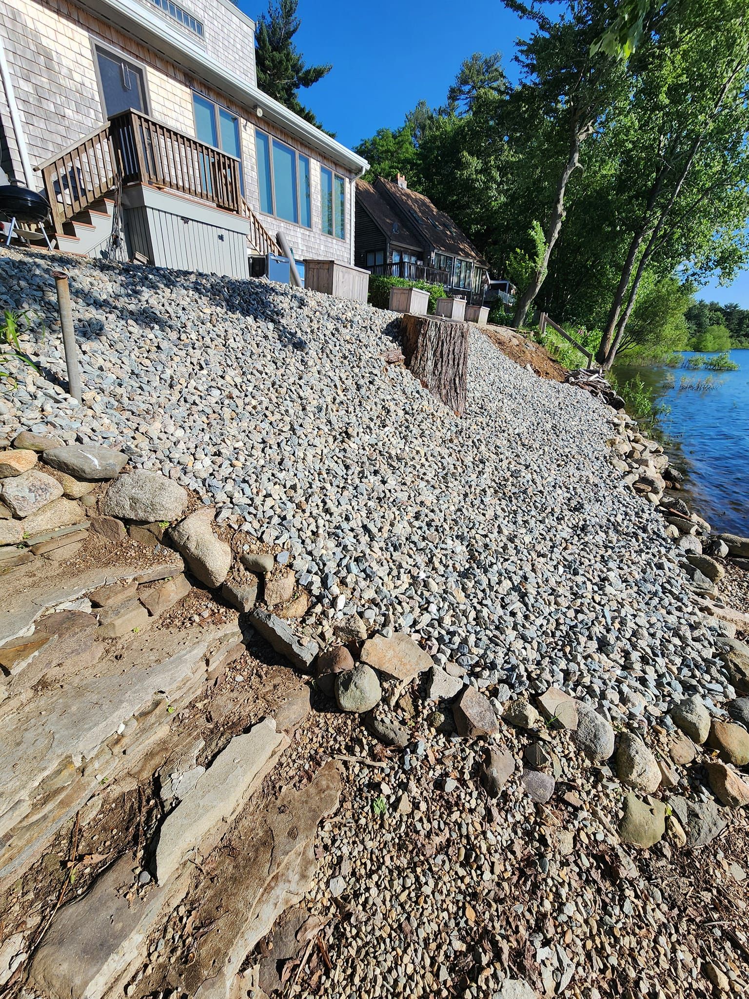 A house is sitting on top of a rocky hill next to a body of water.