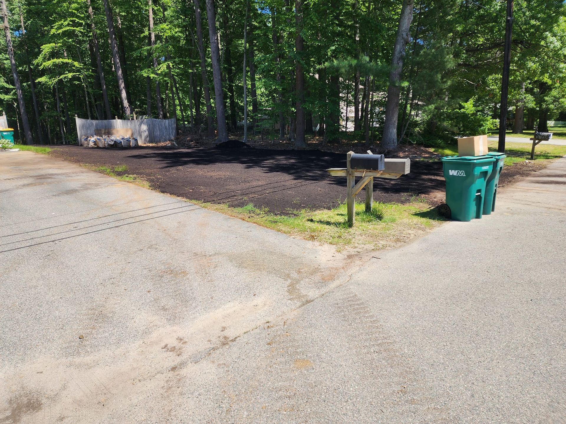 A mailbox and trash cans on the side of a road