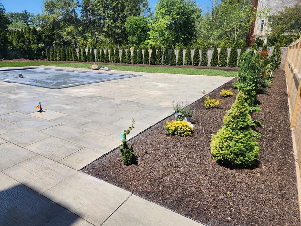 A large concrete patio with a swimming pool in the background.