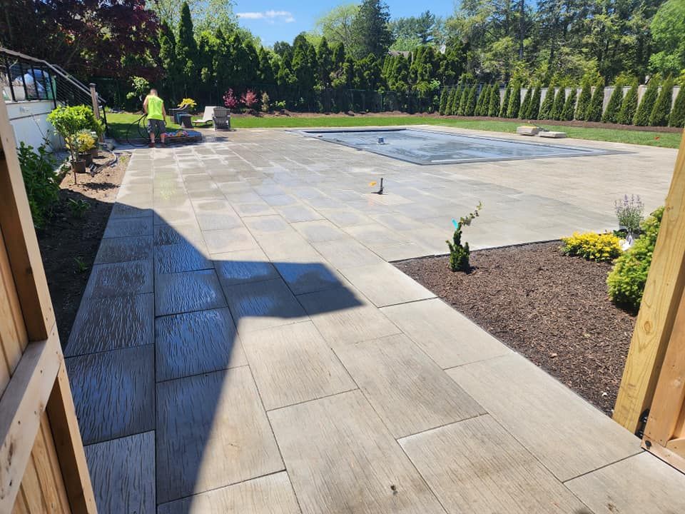A man is standing on a patio next to a pool.